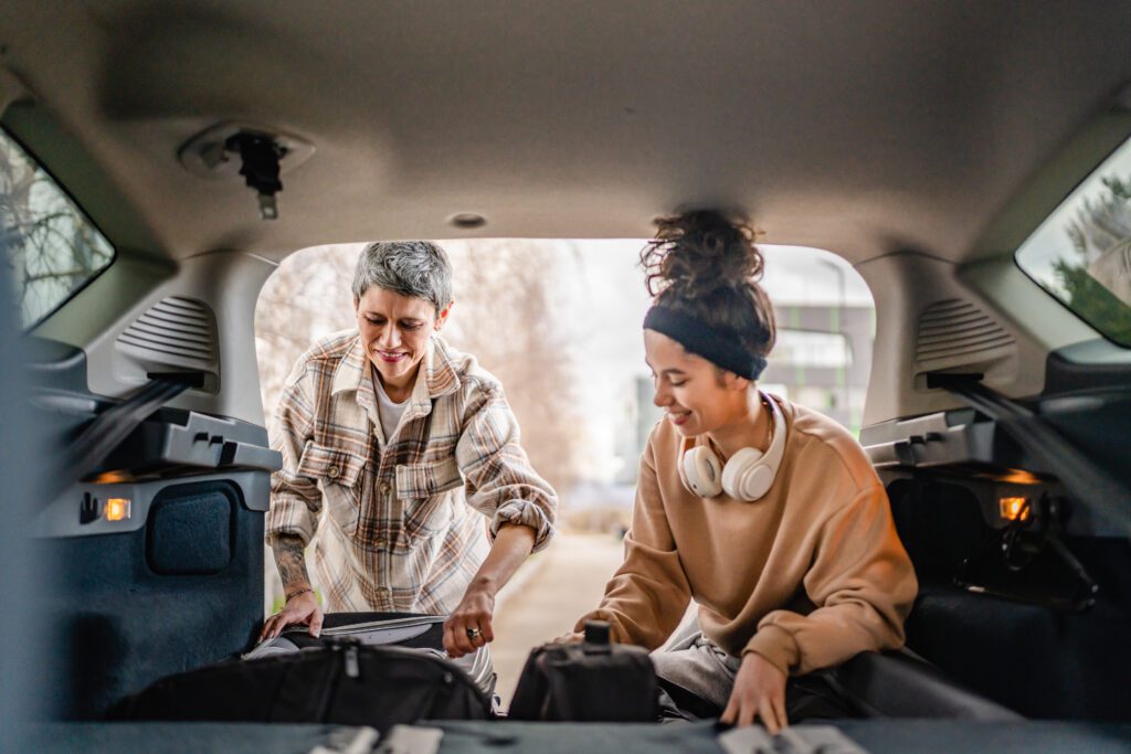 Smiling mother and daughter pack up car