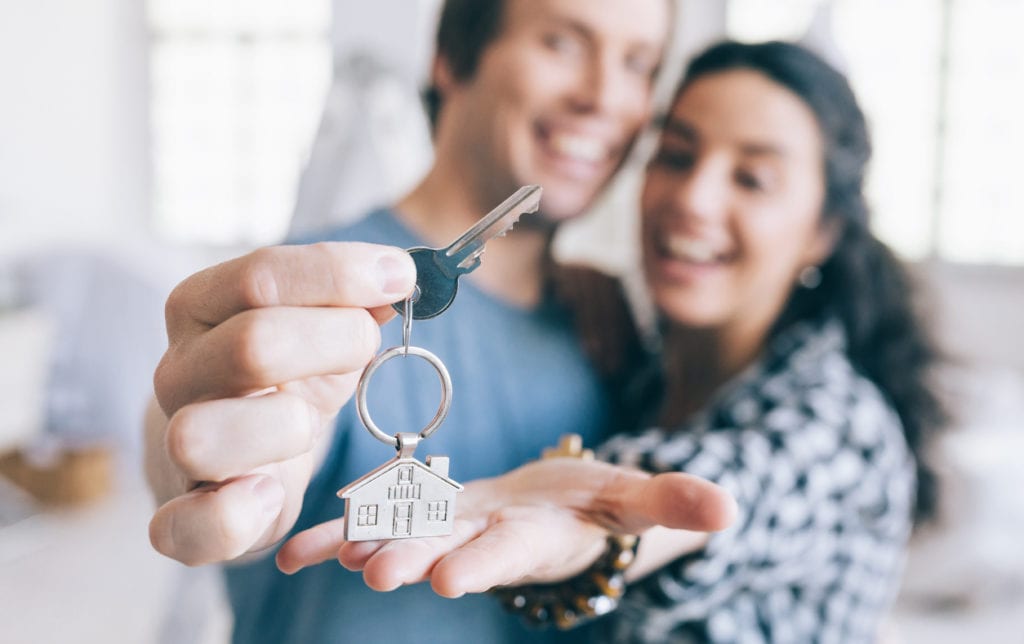 Couple holding key to first home after refinancing student loans