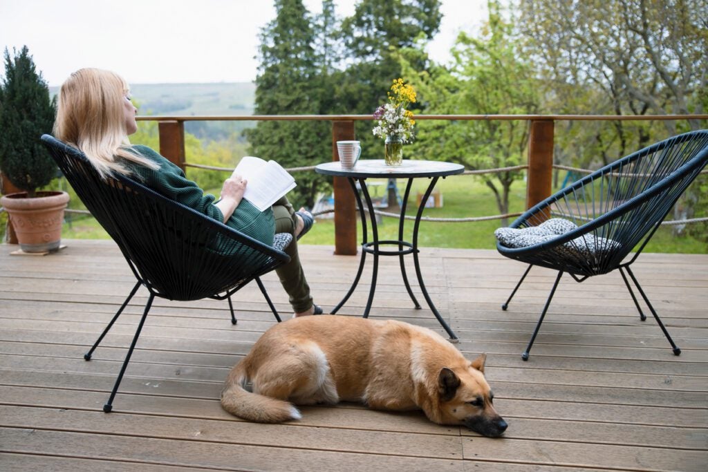 Woman reading book on the porch, resting with her dog