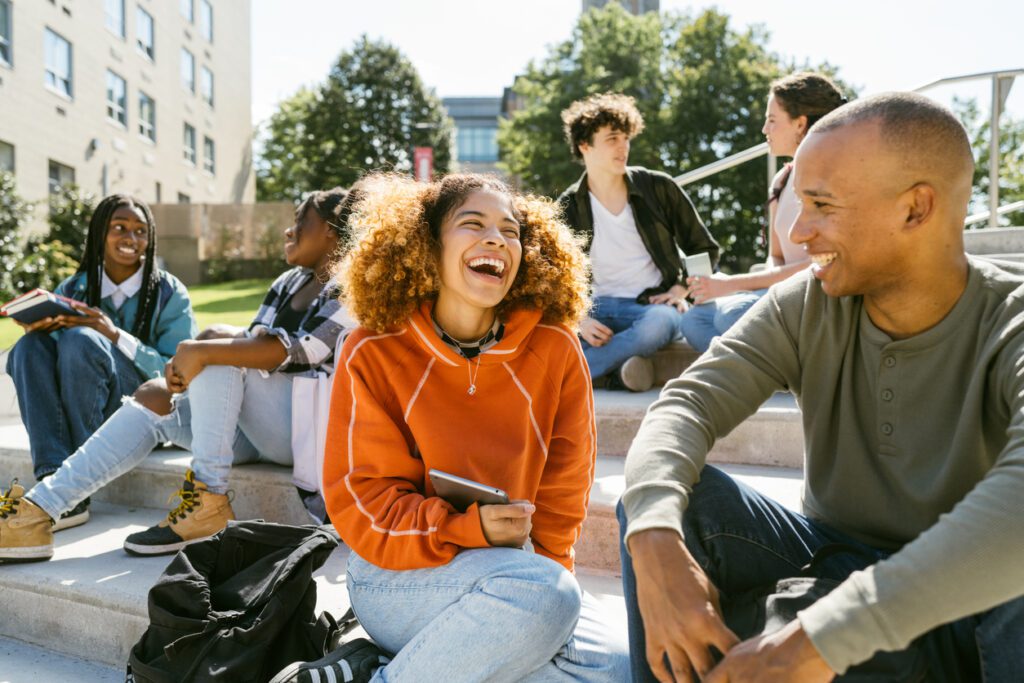 University students hang out in campus talk to each other while sitting on the steps of faculty entrance