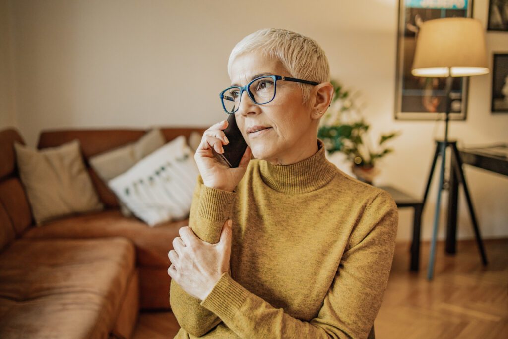 Middle aged woman looking concerned while talking on the phone