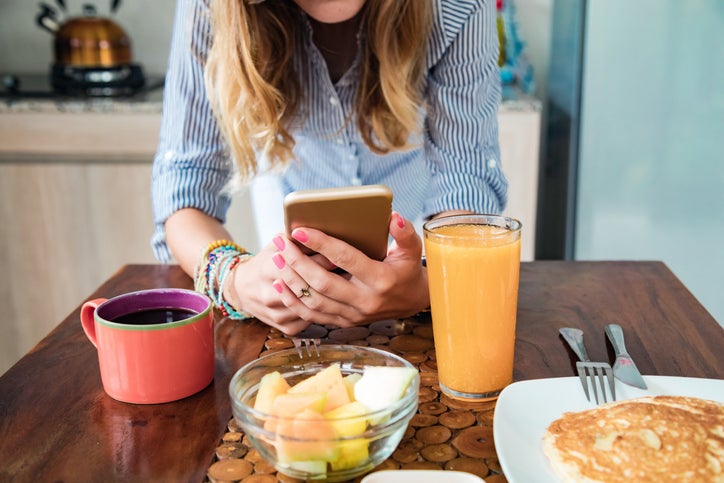 Young adult woman using smartphone in a modern home.