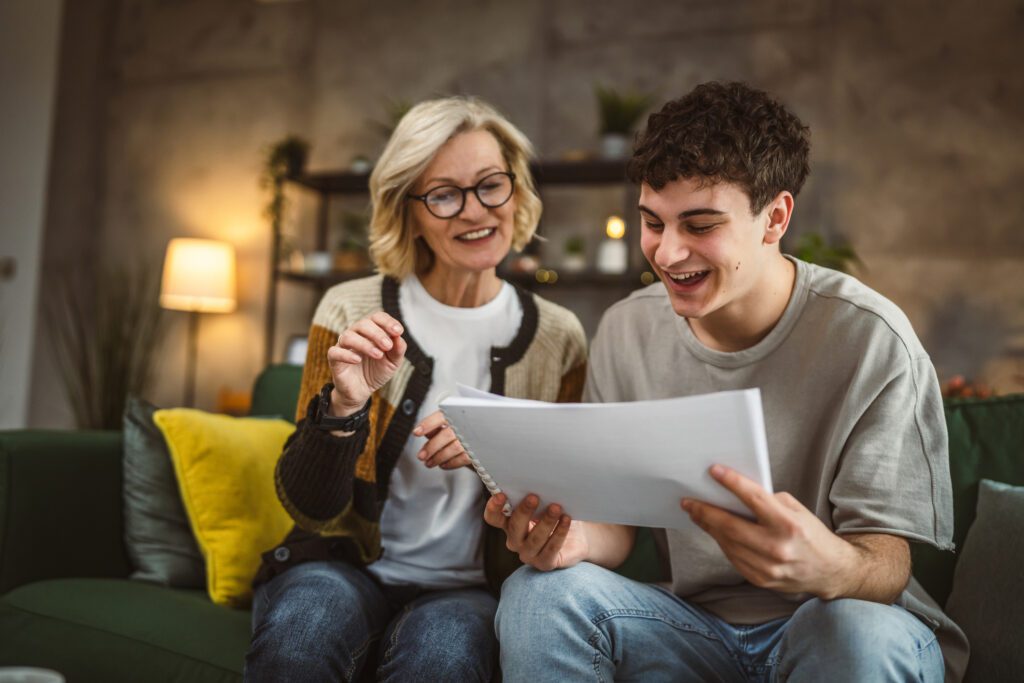 Mother and son reviewing documents happily on couch