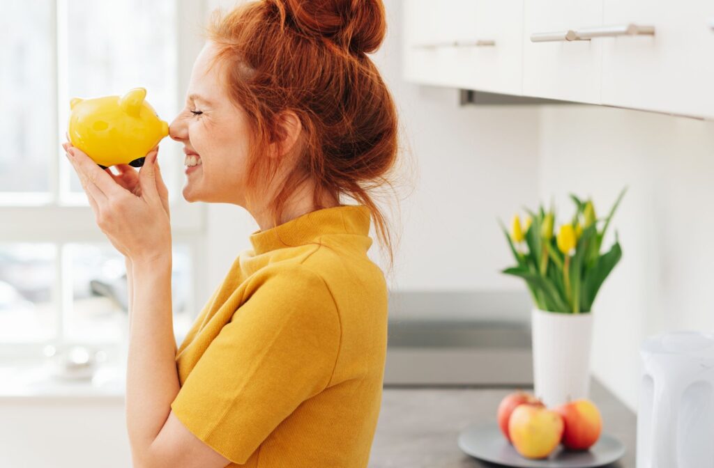 Red headed female smiling with piggy bank