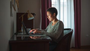 Woman sitting in low light in front of laptop