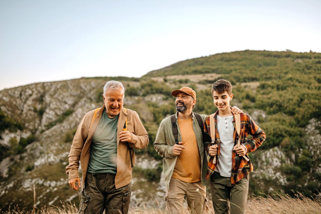 Elderly father with adult son and grandson admiring nature on a picnic