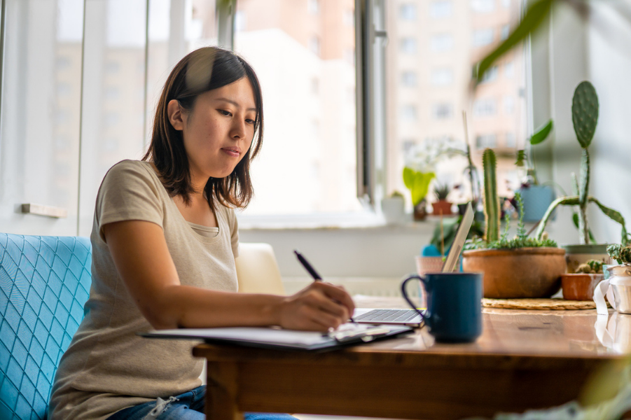 Young Asian woman sitting at a table creating a budget.