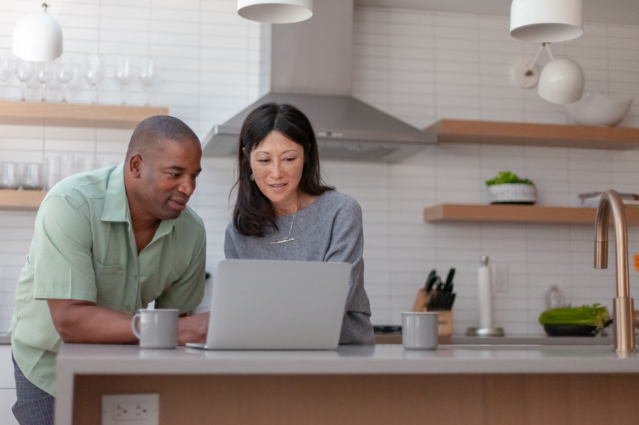 Mixed race couple looking at laptop in their kitchen