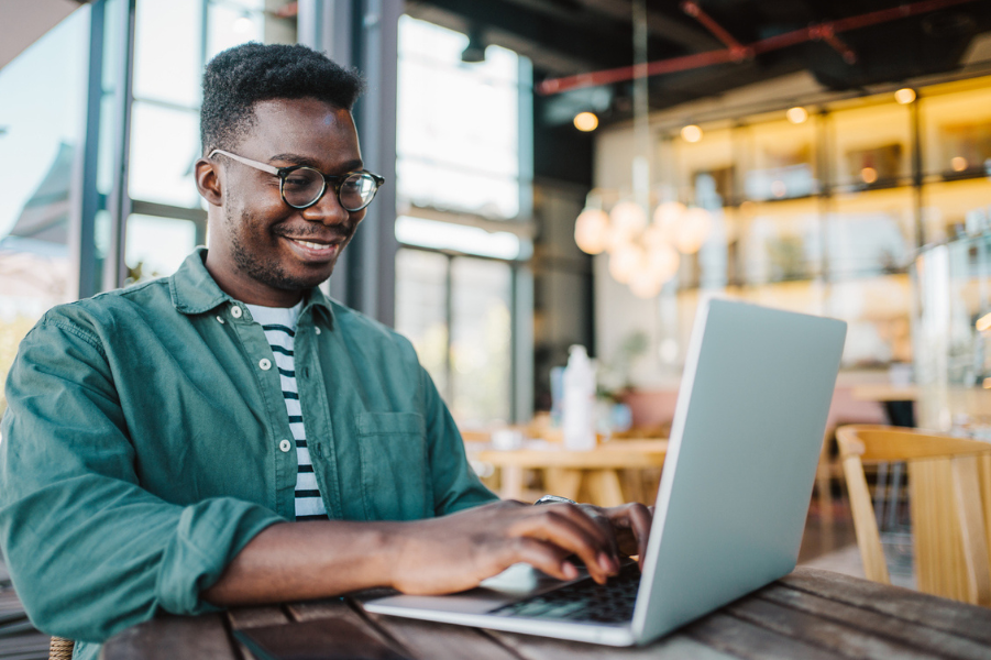 Young black male sitting in coffee shop on laptop.