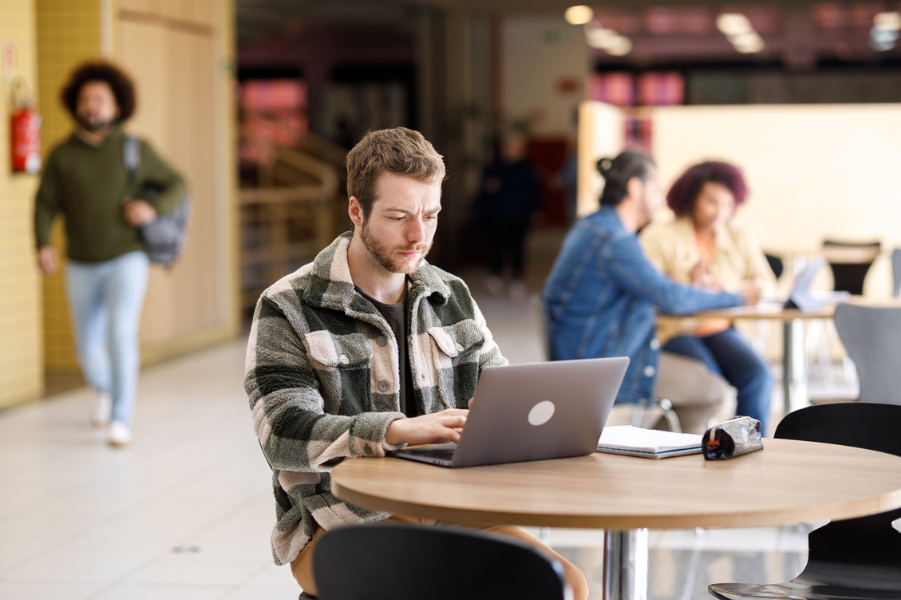 College student sitting in common area on computer.