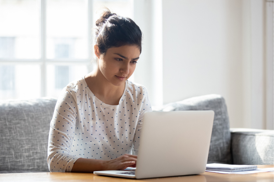 Young woman sitting at a table in her house on her laptop.