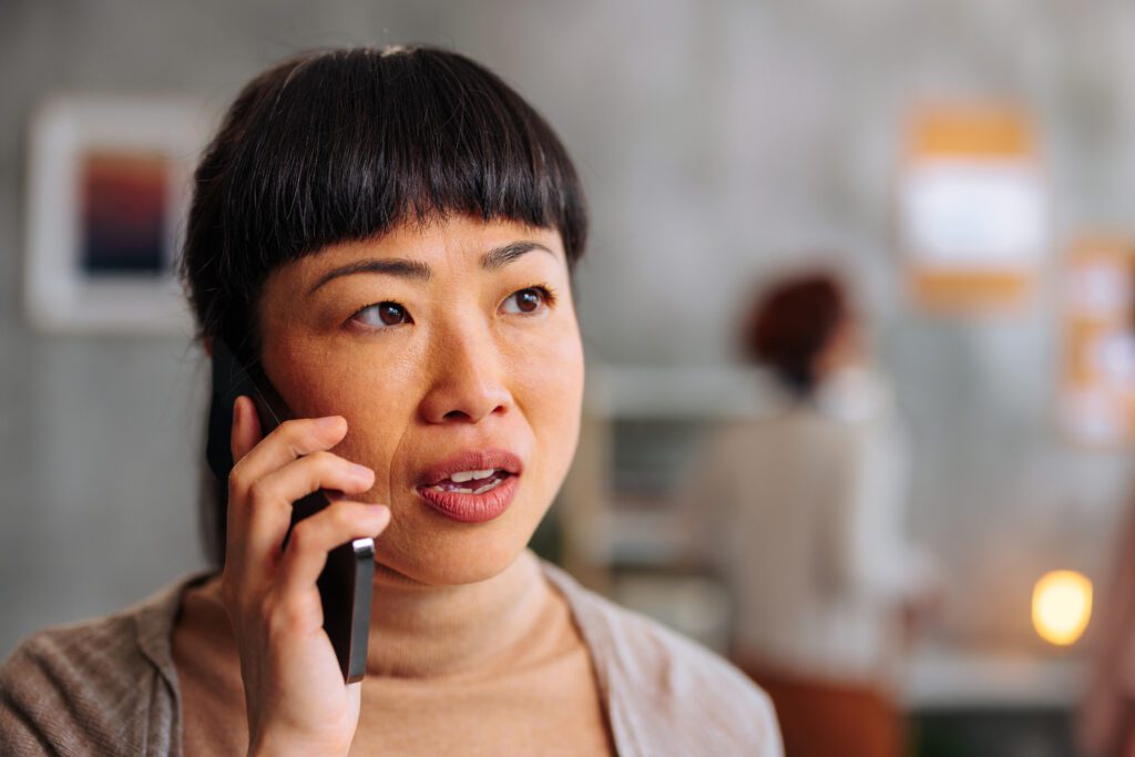 Close up portrait of an Asian woman mildly shocked on phone