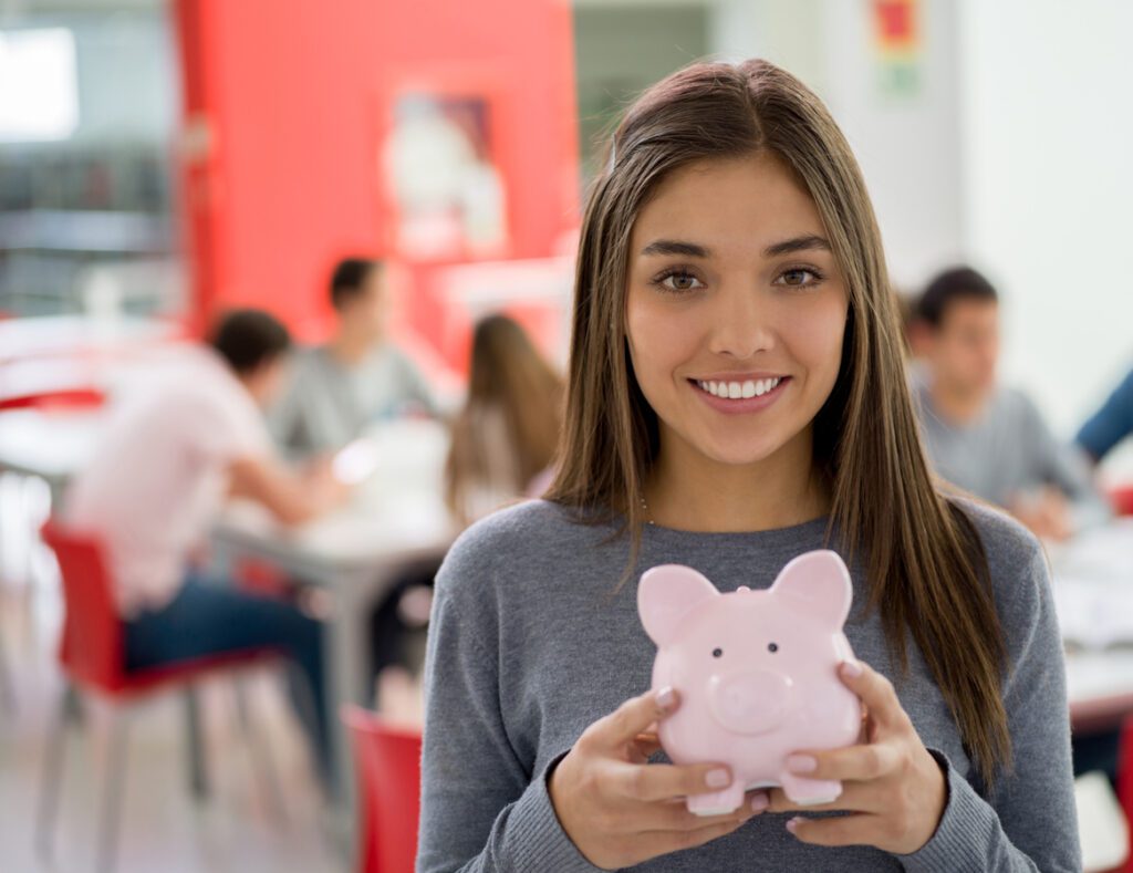 female student at the library holding a piggy bank