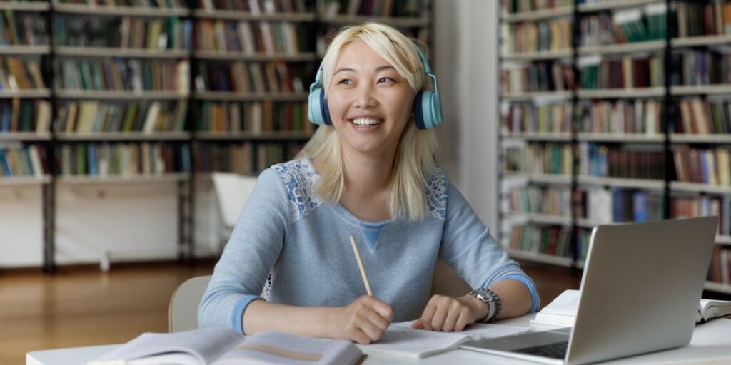 Young female asian student sitting in college library researching student loan payments.