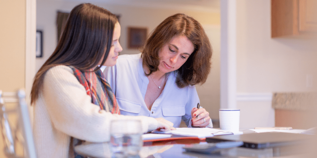 Mother looking over student loan paperwork to cosign loan for daughter.