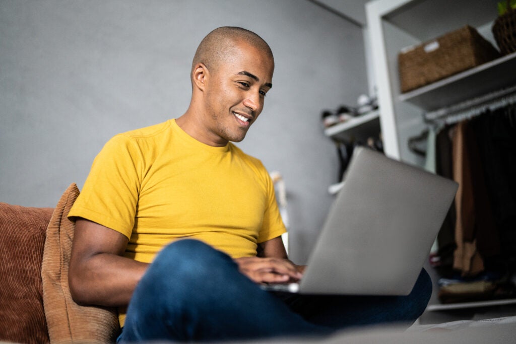 Young man using their laptop to research the best student loan rates.