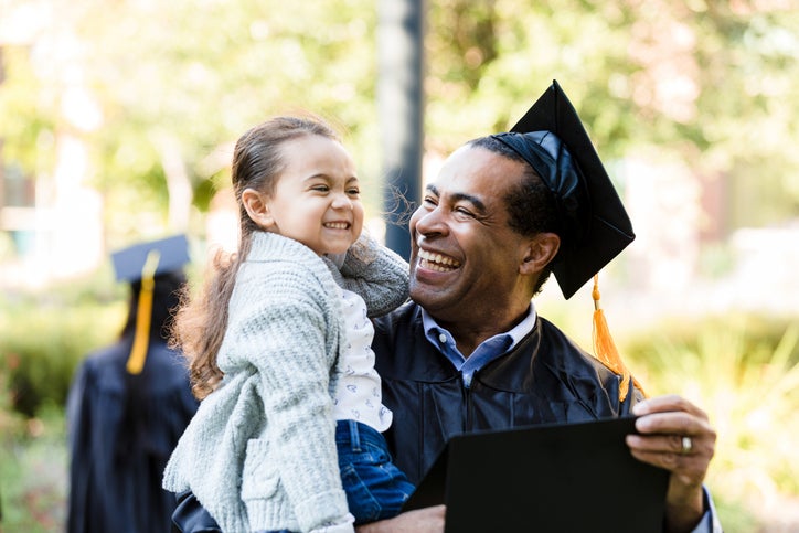 Little girl makes graduating grandfather laugh with silly face