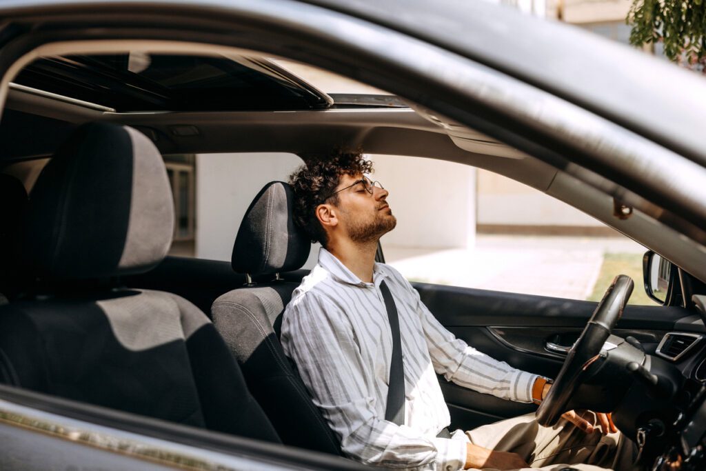 Tired young well dressed man sitting in car